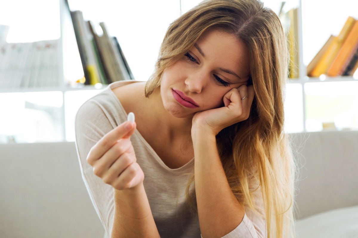 young woman looking at oblong white pill