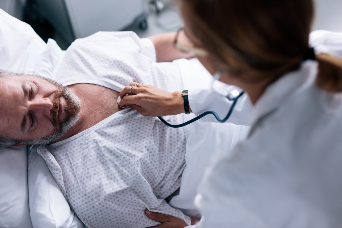 Top view shot of doctor taking heartbeats of sick patient. Hospitalised man getting examined by female physician.