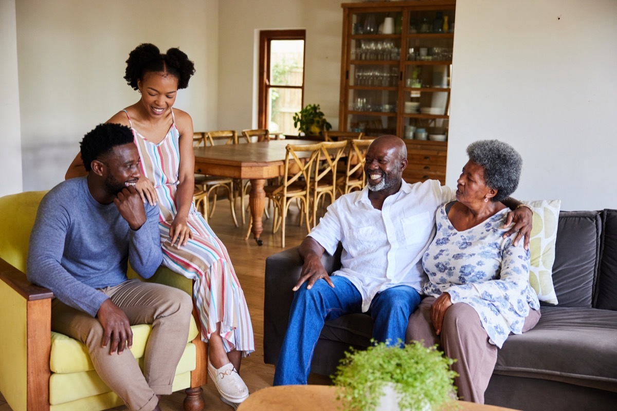 Senior couple and their daughter and son-in-law talking and laughing together at home during a visit