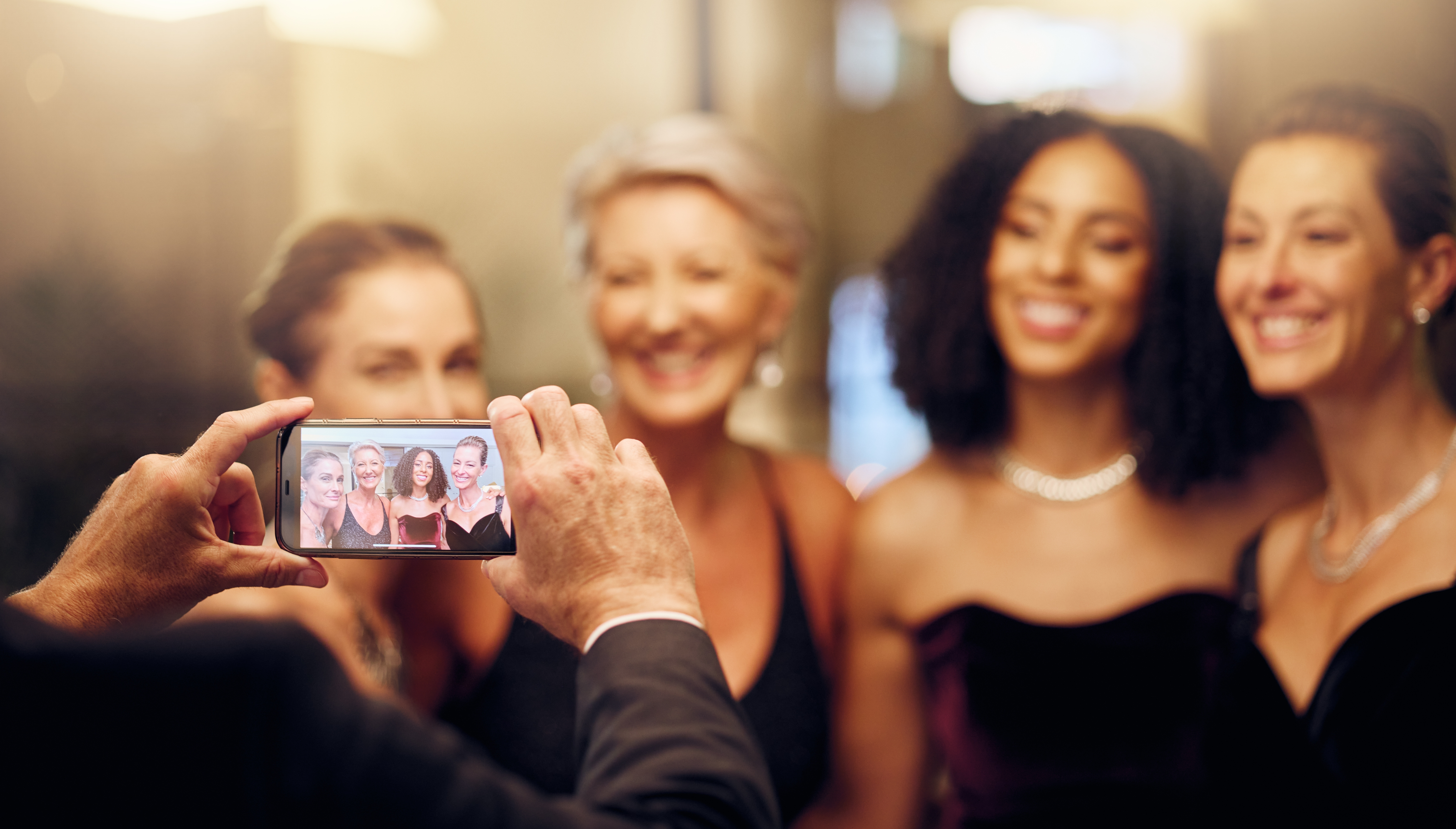 Group of four middle-aged female friends wearing cocktail dresses posing for a picture