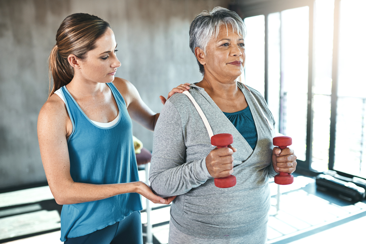 Personal trainer showing woman how to lift weights properly.