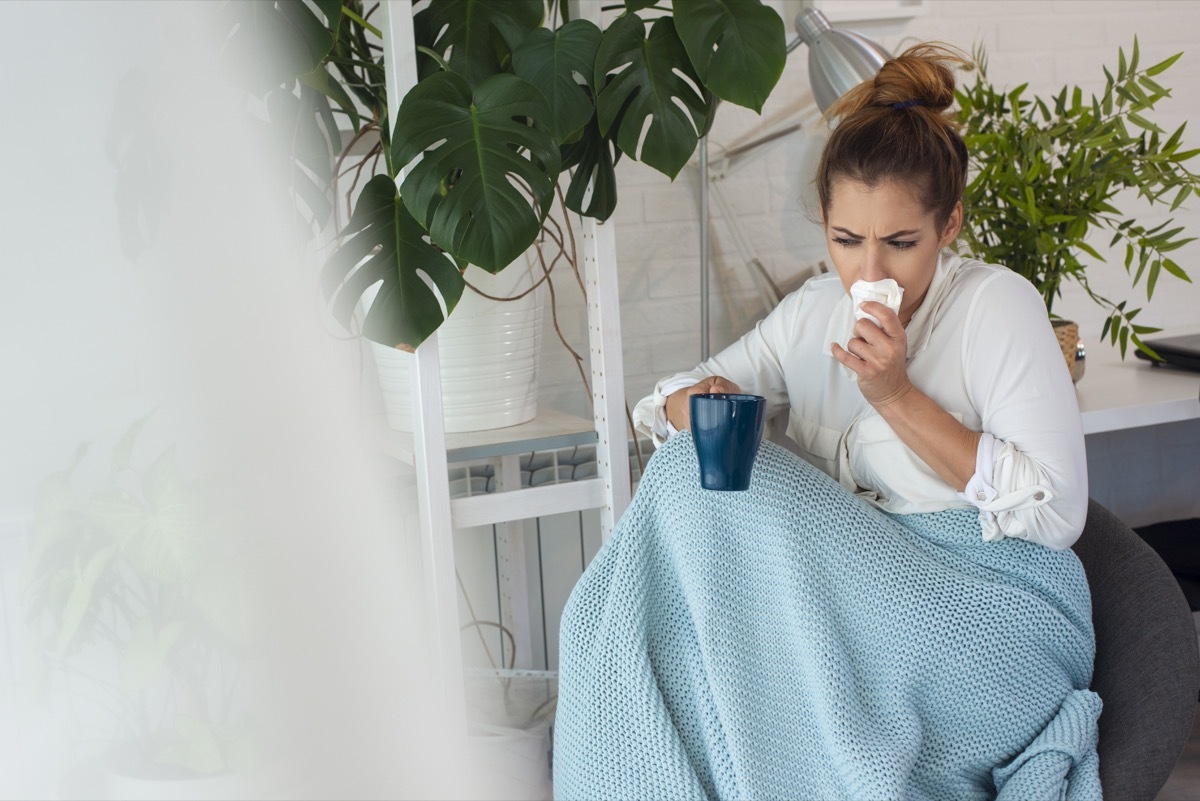 Young ill woman sitting on lounge at home