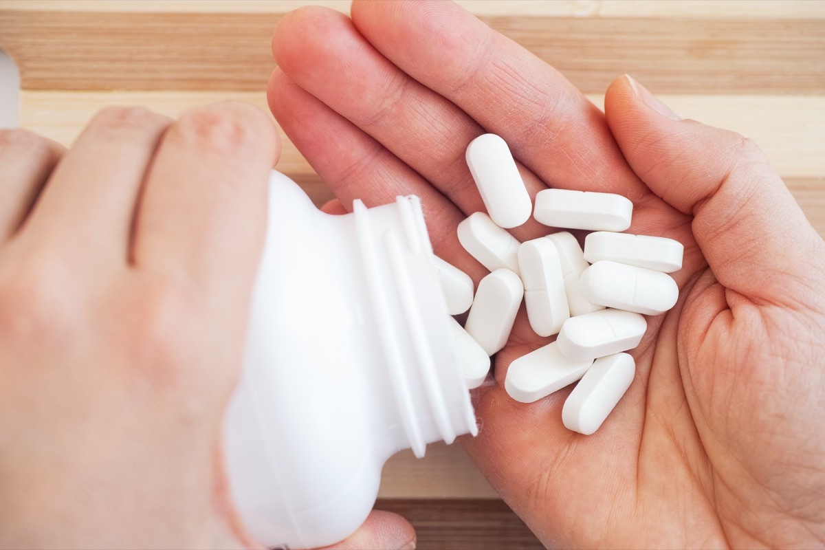 Woman taking magnesium pills out of a bottle. Close up.