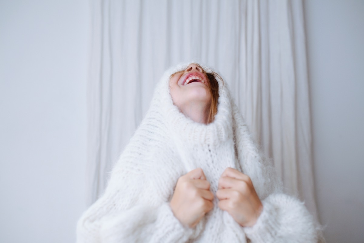 young white girl putting on sweater