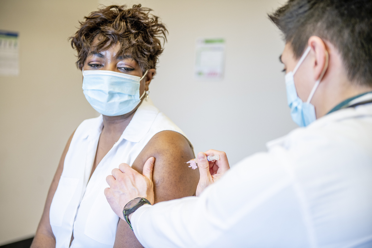 A senior woman of is getting her COVID-19 vaccine injection from a male medical doctor.