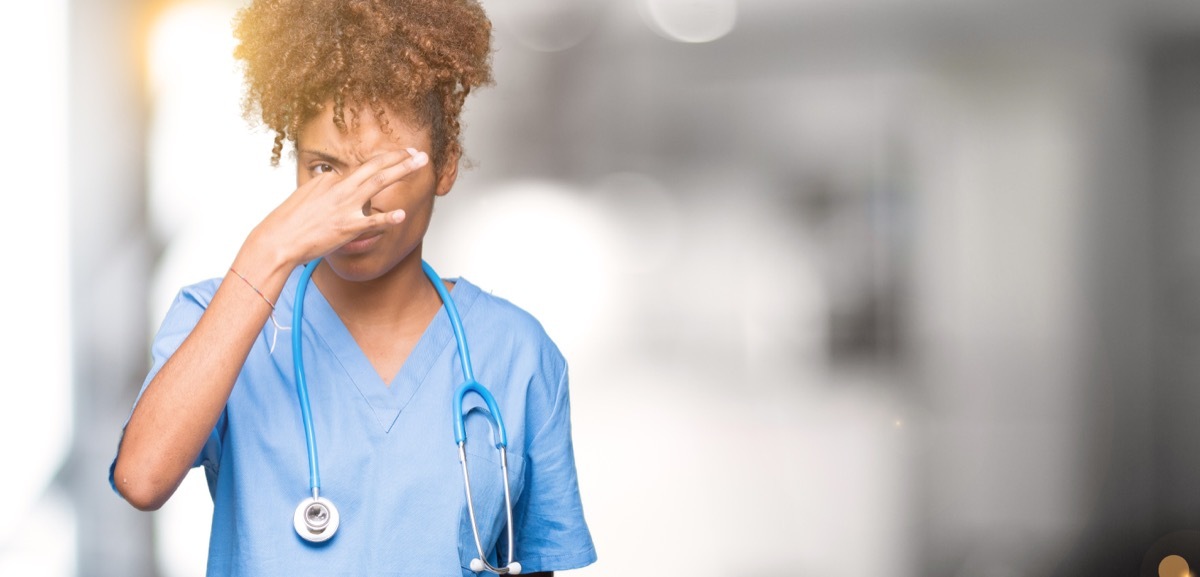 doctor woman over isolated background smelling something