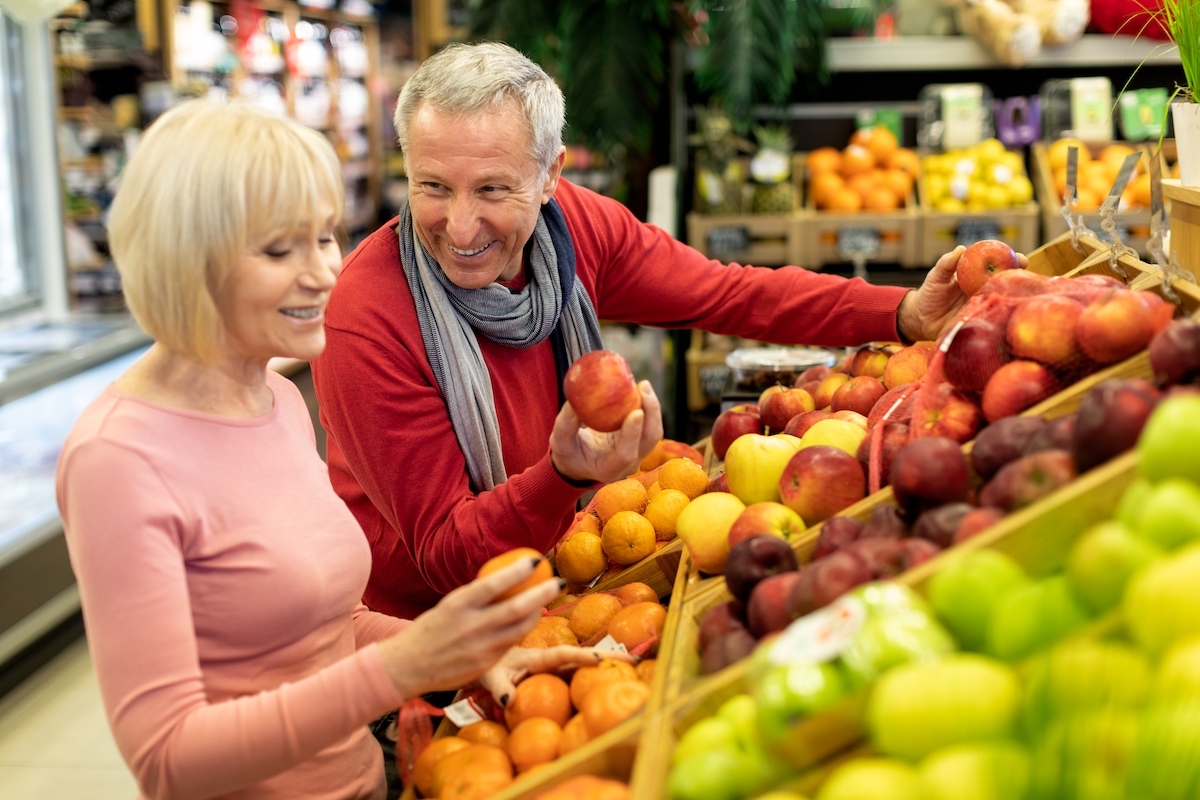 A happy older couple picking out produce together at the grocery store.