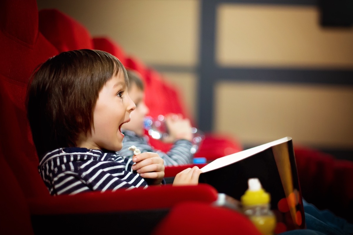 kids watching a movie in the theater and eating popcorn