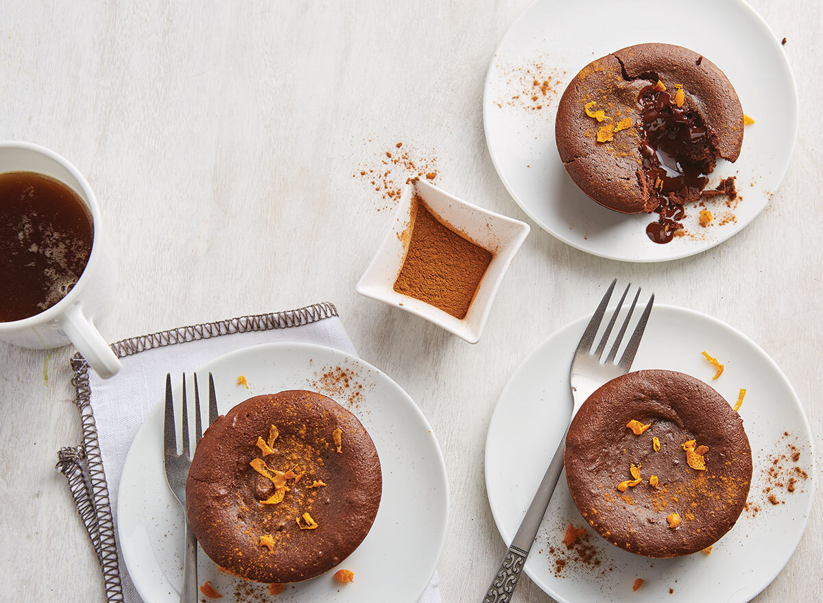 cinnamon orange lava cakes on white plates with forks and coffee and cinnamon pinch bowl