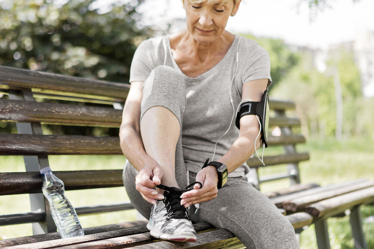 Older woman in athletic wear tying sneaker