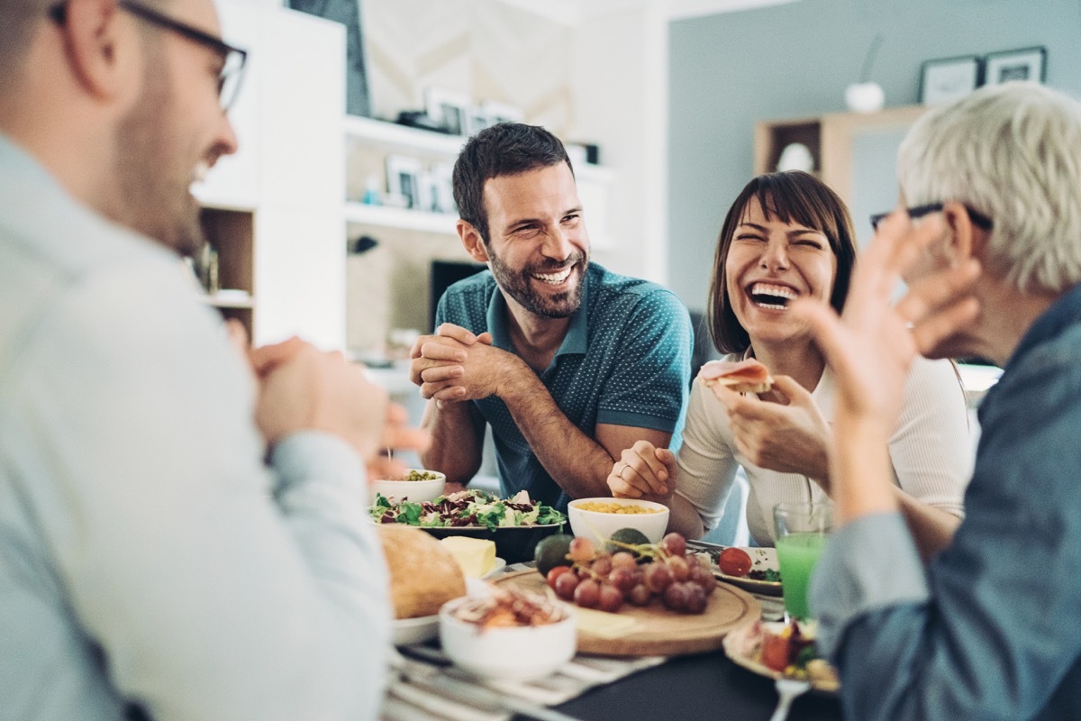 Group of friends gathered around the table with food and drinks, having good time together