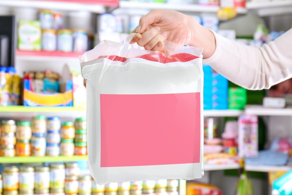 Woman with pack of baby diapers in shop