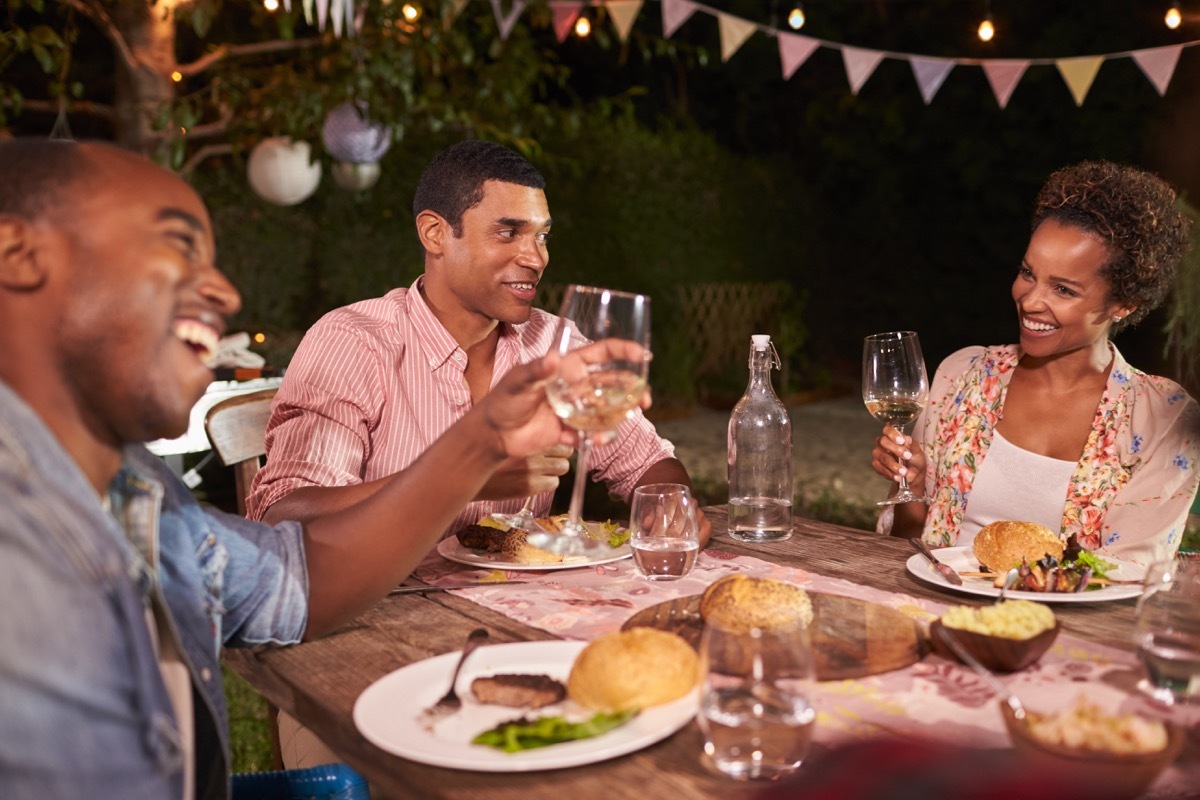 group of three 30-something black friends eating together outside