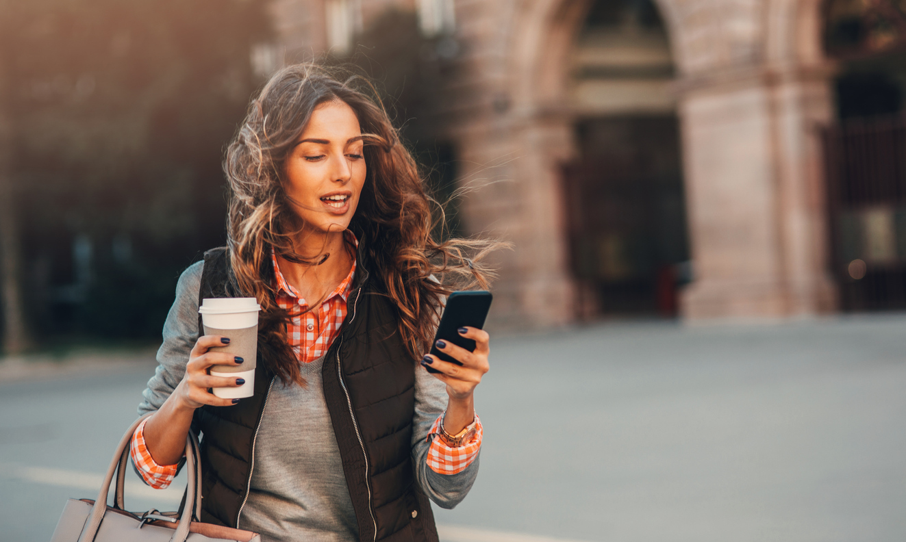 Woman surfing the net while drinking coffee outdoors.