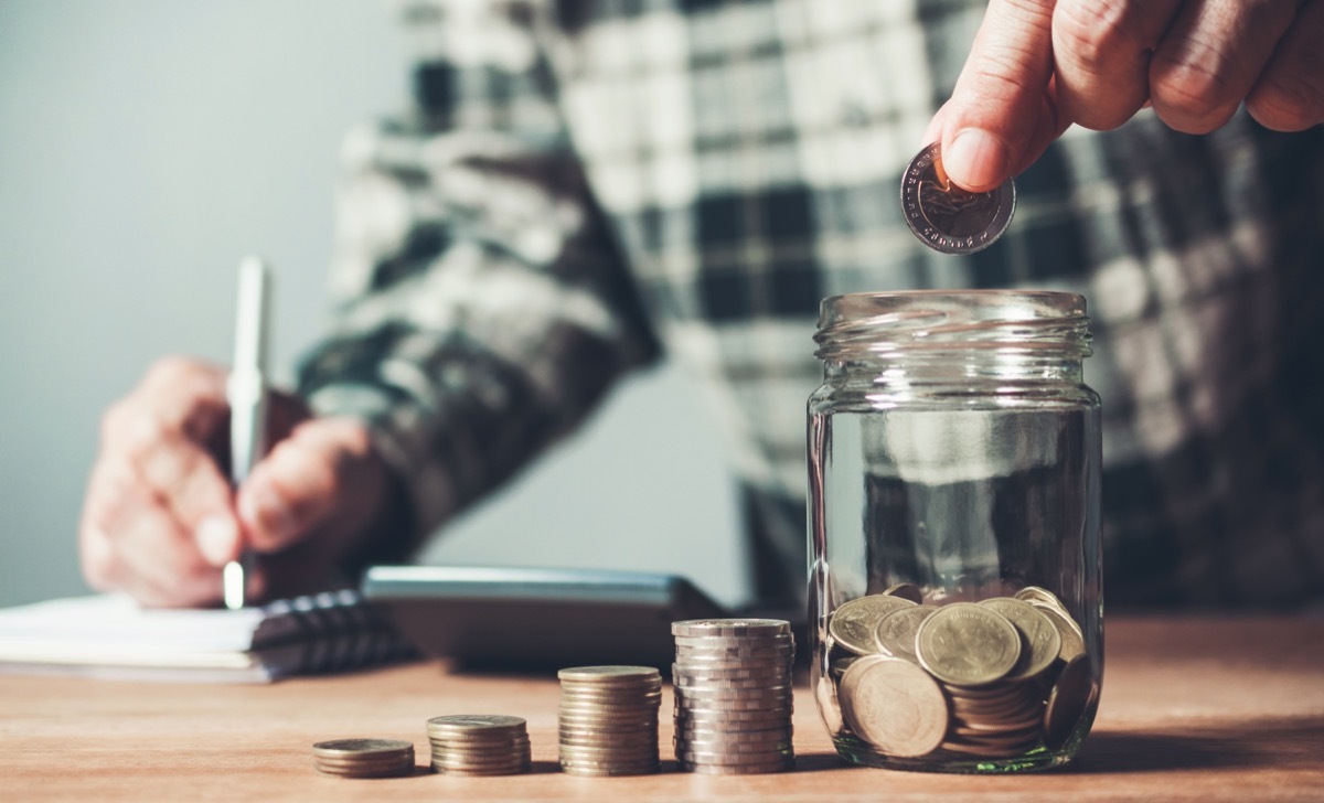 man putting coins in a jar