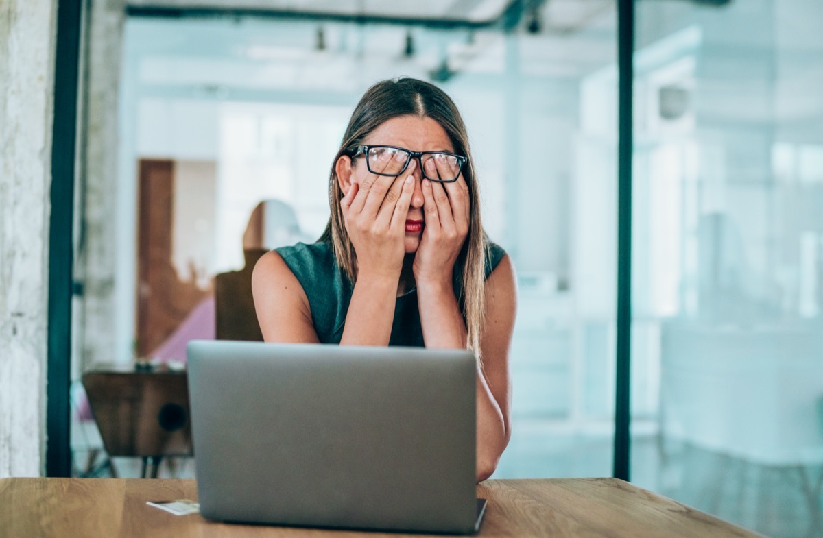 Stressed businesswoman rubbing her eyes in the office.