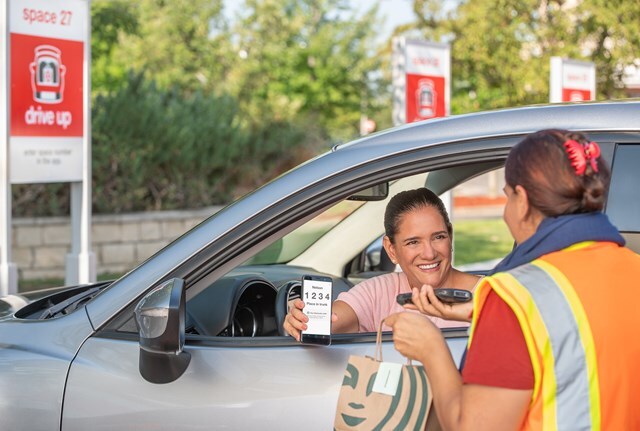 A Target employee delivering a Starbucks order to a customer doing drive-up service.