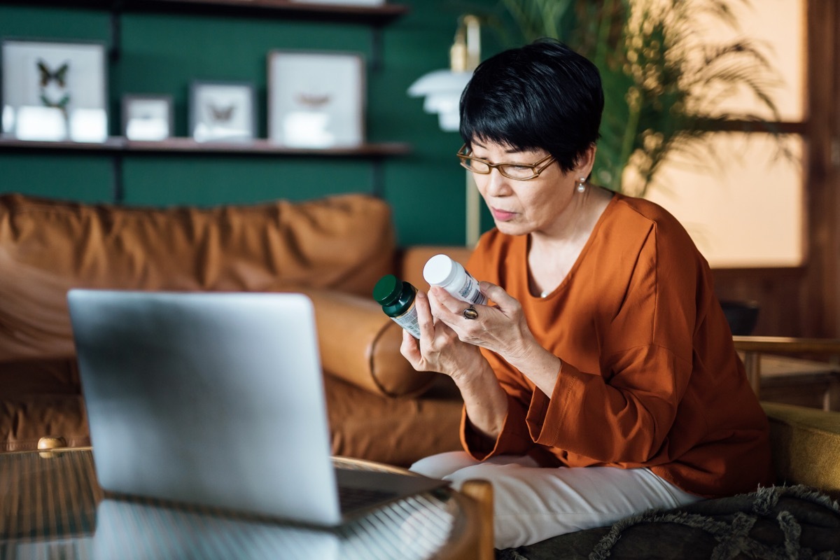 Mature woman having a virtual appointment with doctor online, consulting her prescription and choice of medication on laptop at home. 