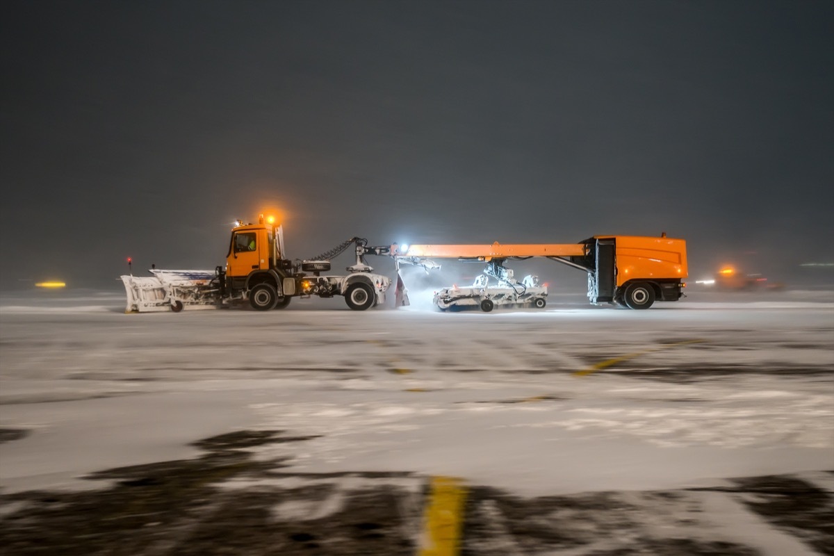 orange jet sweeper cleaning snow on airport ground