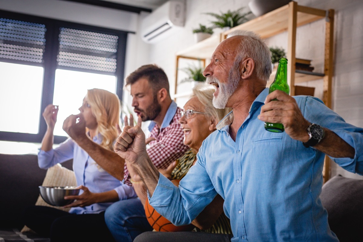 two-generation family is watching a sports game and cheering