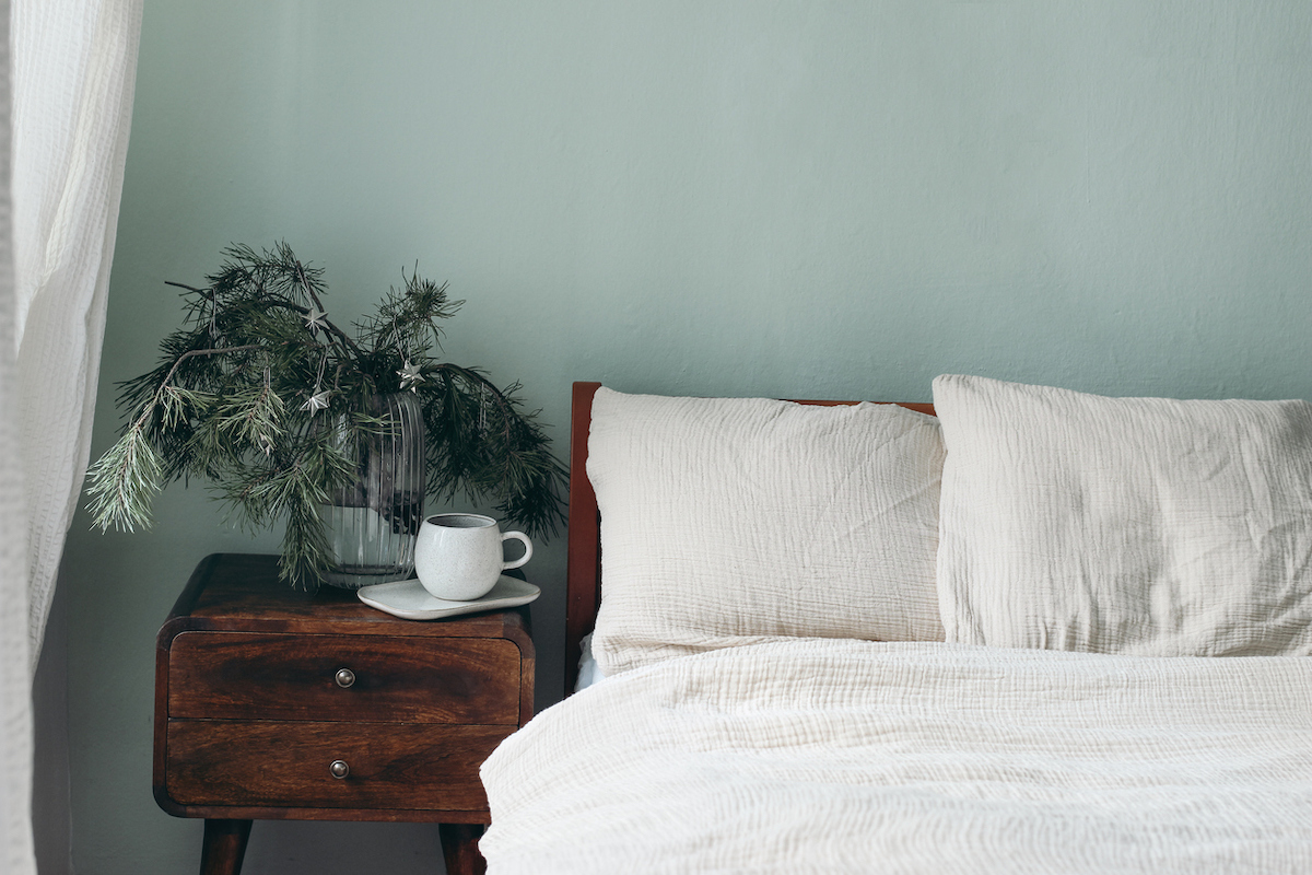 Close up of a bed white white sheets against light green walls