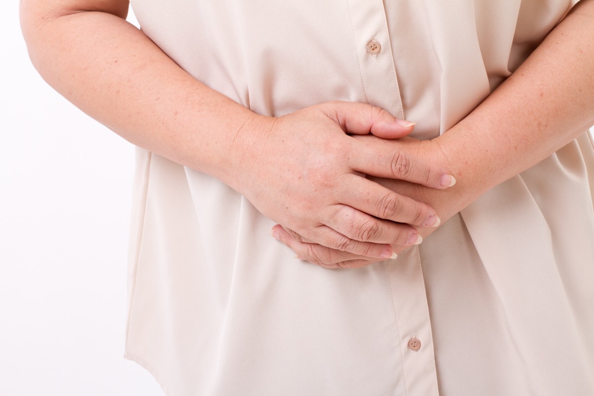 older woman in pain, holding her stomach, subtle symptoms of serious disease