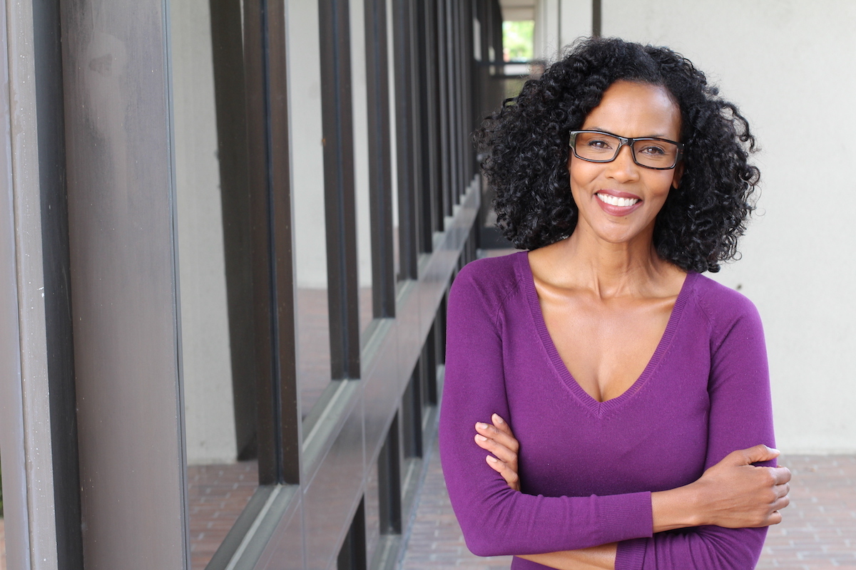 Portrait of professional black businesswoman smiling and wearing a purple v-neck sweater