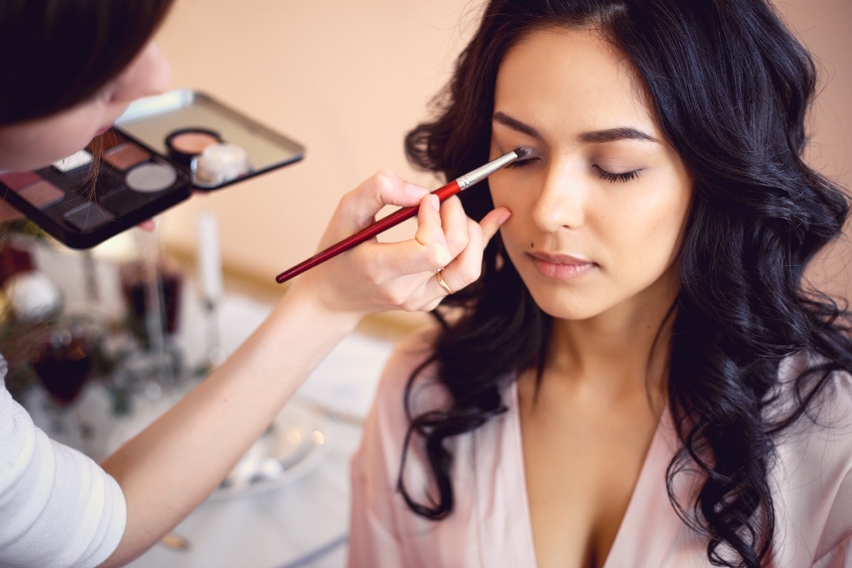 Makeup artist applying eyeshadow on woman