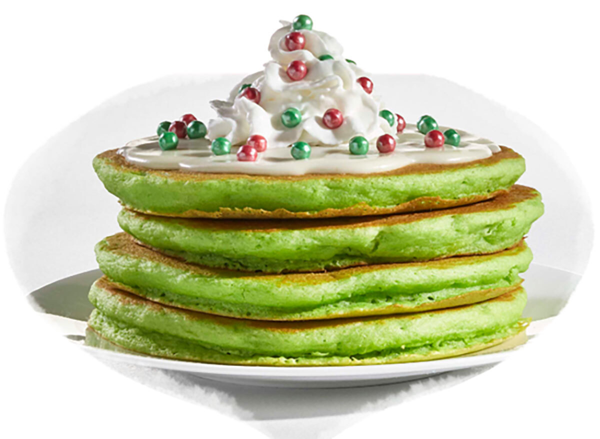 stack of green elf on the shelf pancakes from ihop topped with whipped cream and red and green candy pieces