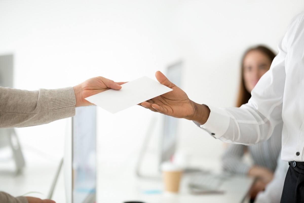 Close up of male CEO giving envelope to successful office worker with reward or money bonus for high work results, boss supporting motivating employee. Achievement, promotion, stimulation, HR concept