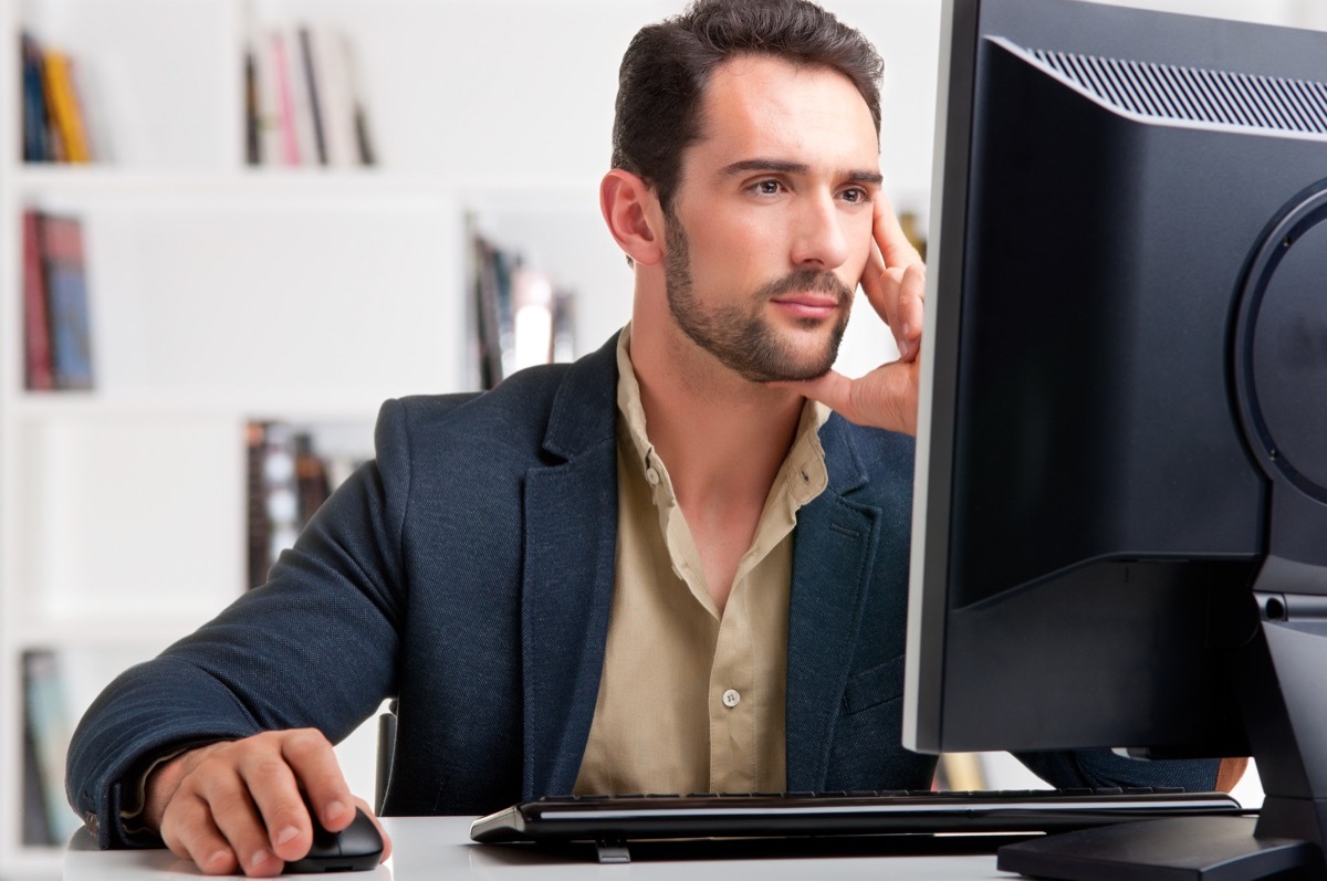 middle aged white man working at large computer monitor while working from home at wfh office