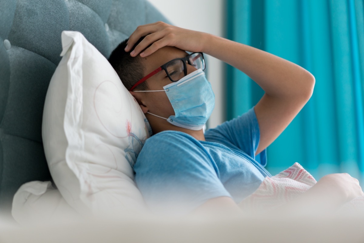 Teenage boy sick in bed with Covid-19 symptoms