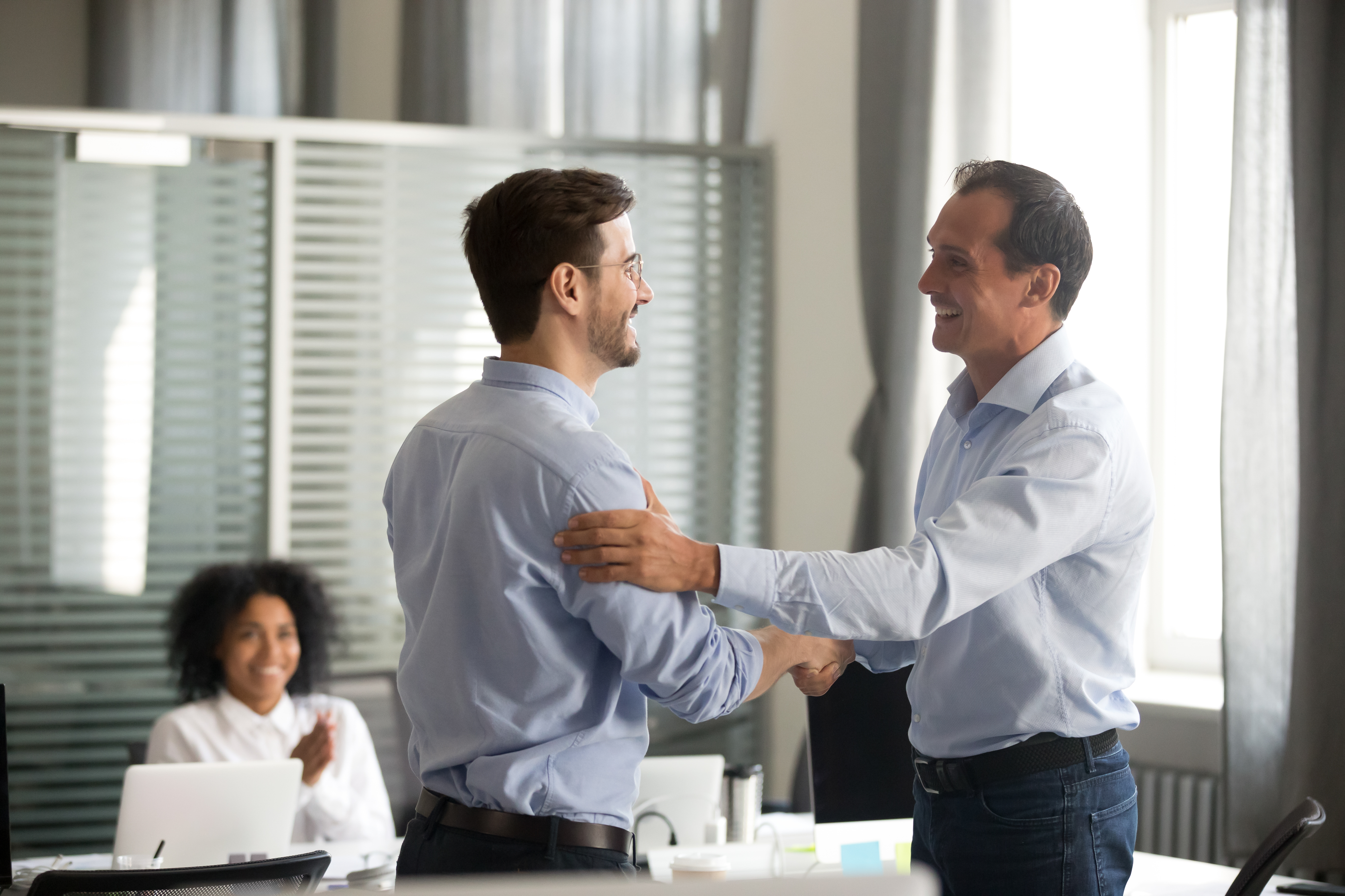 two male businessmen shaking hands and smiling in the office