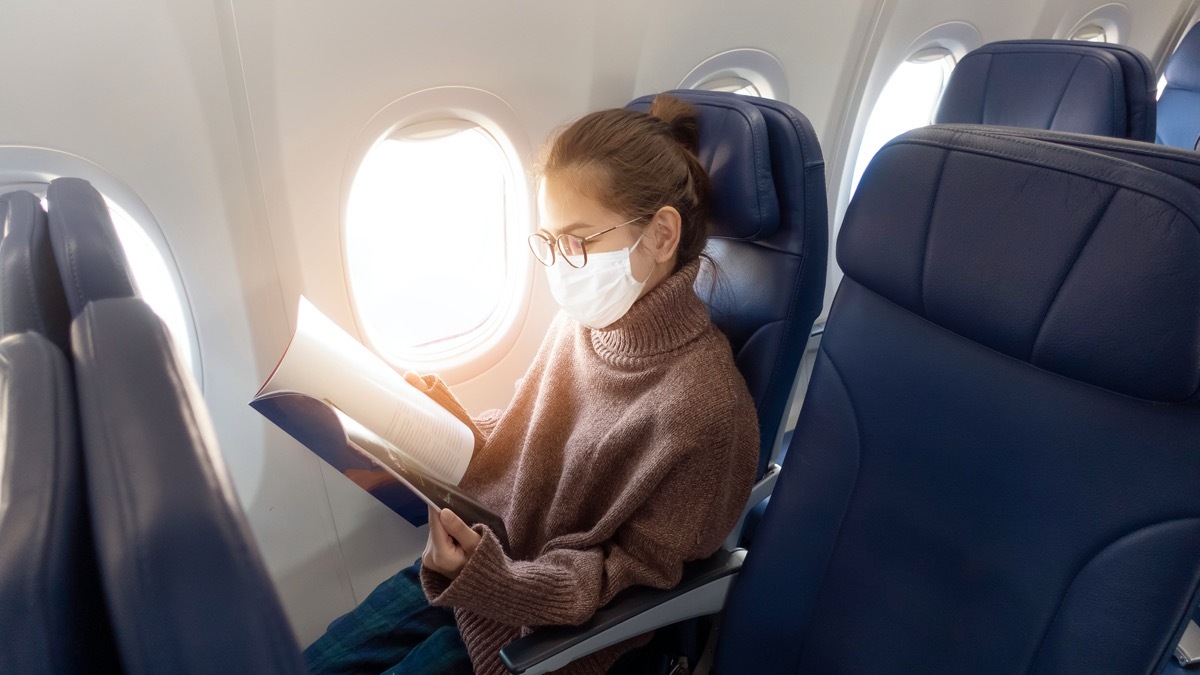 A young woman wearing face mask is traveling on airplane , New normal travel after covid-19 pandemic