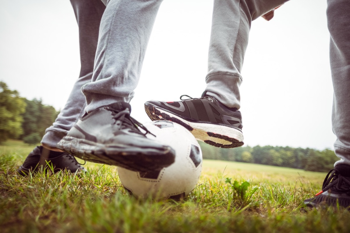 two men playing soccer in gray sweatpants on grass