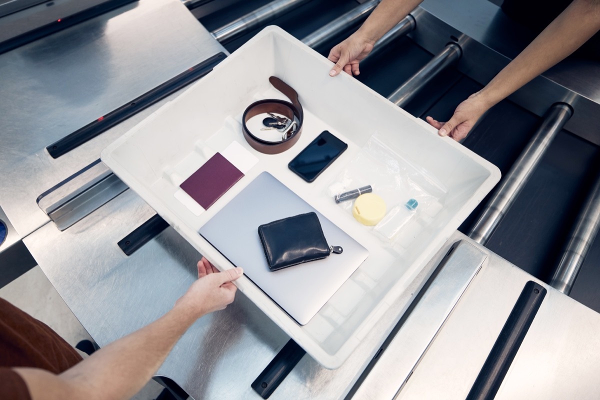 Personal Items, liquids, and laptop in container during control at airport security check before flight.