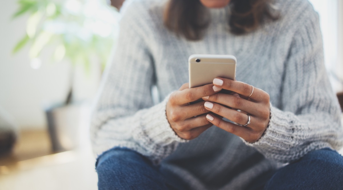 young woman in turtleneck texting on smartphone