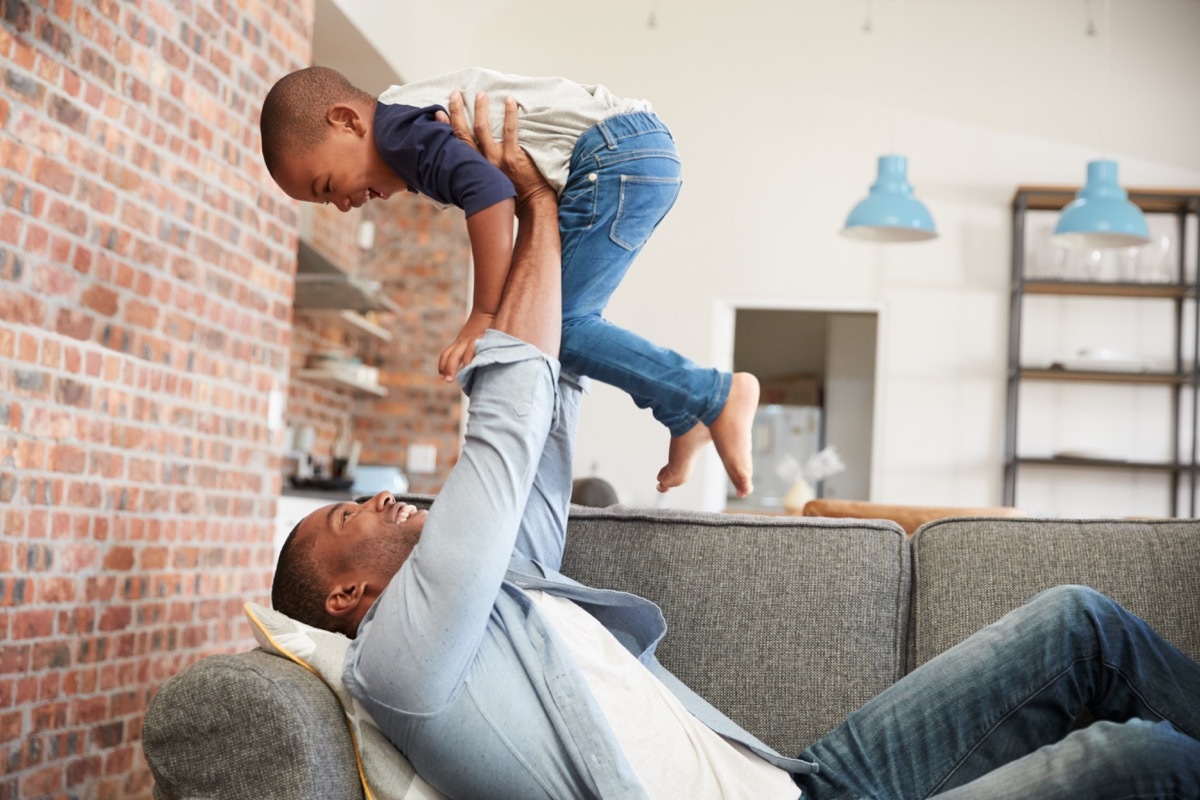 Father And Son Having Fun Playing On Sofa Together