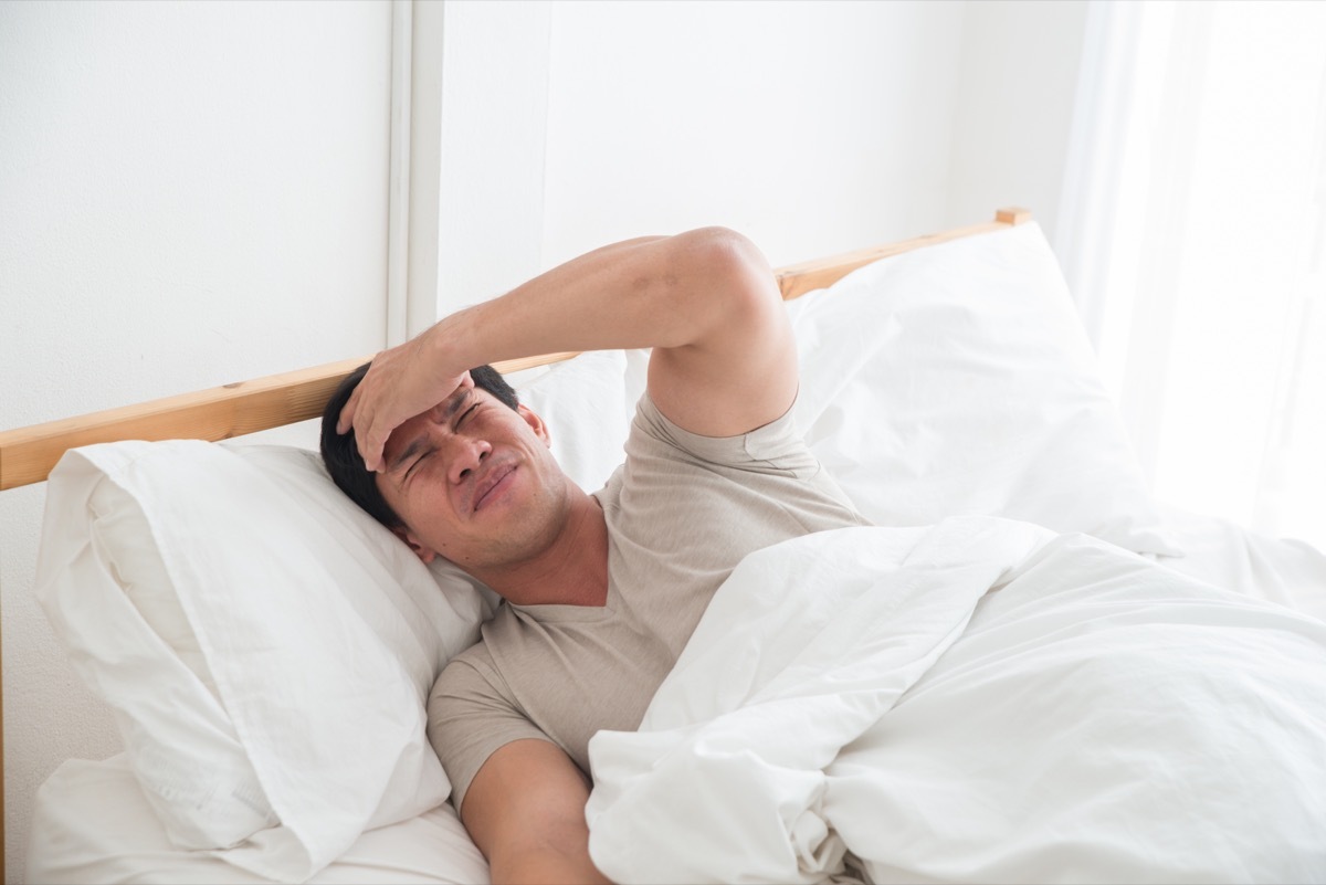 Asian man in bed with a headache