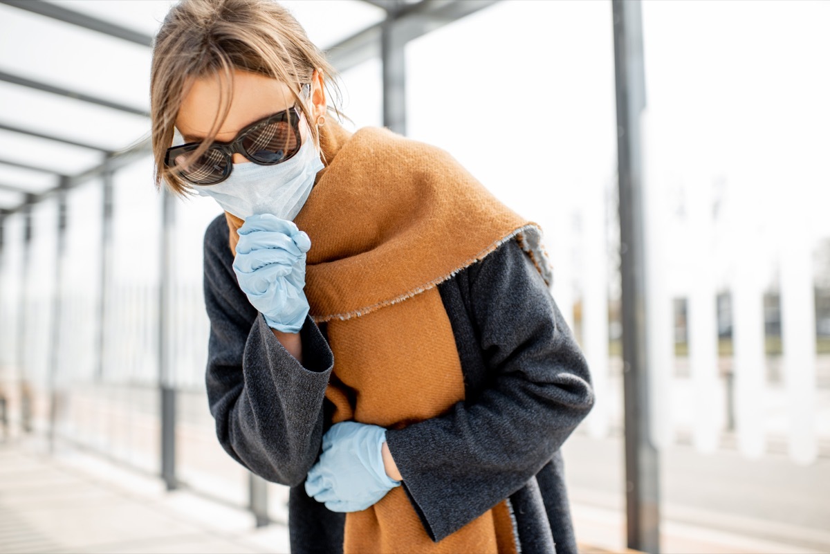 Woman in face mask coughing outdoors