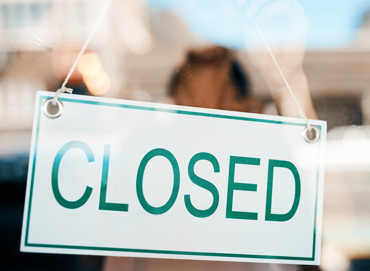 A closed sign hanging the the front door of a restaurant or store