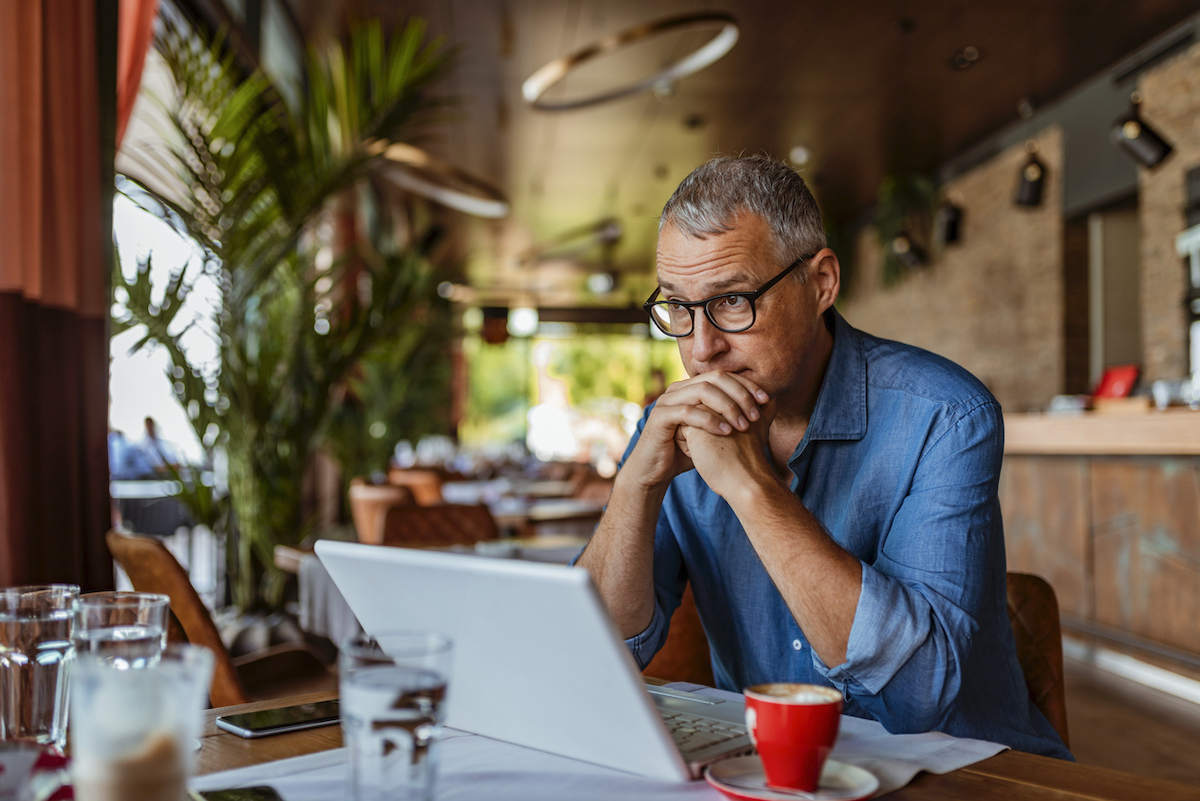 stressed middle aged man feeling sad at laptop