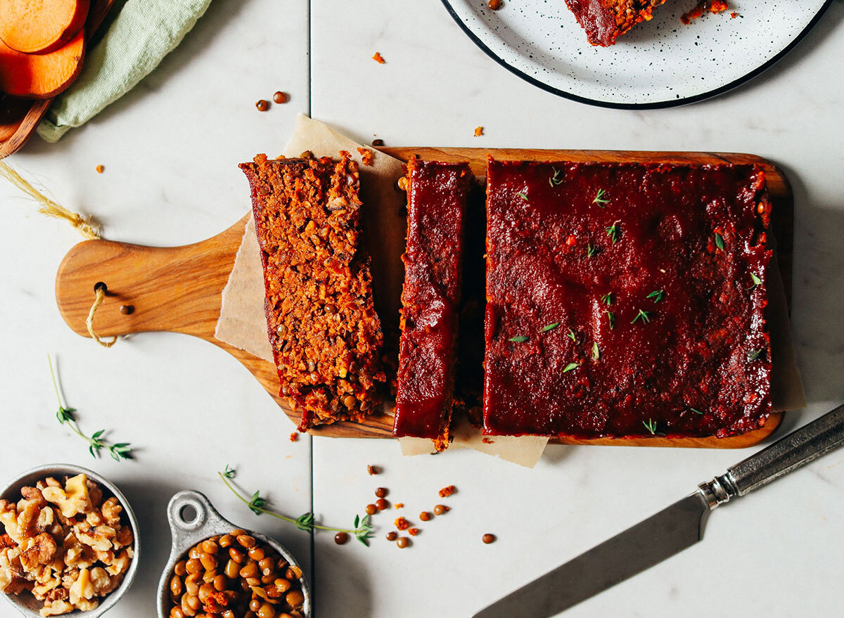 vegan lentil nut meatloaf slices on cutting board with nuts on the side