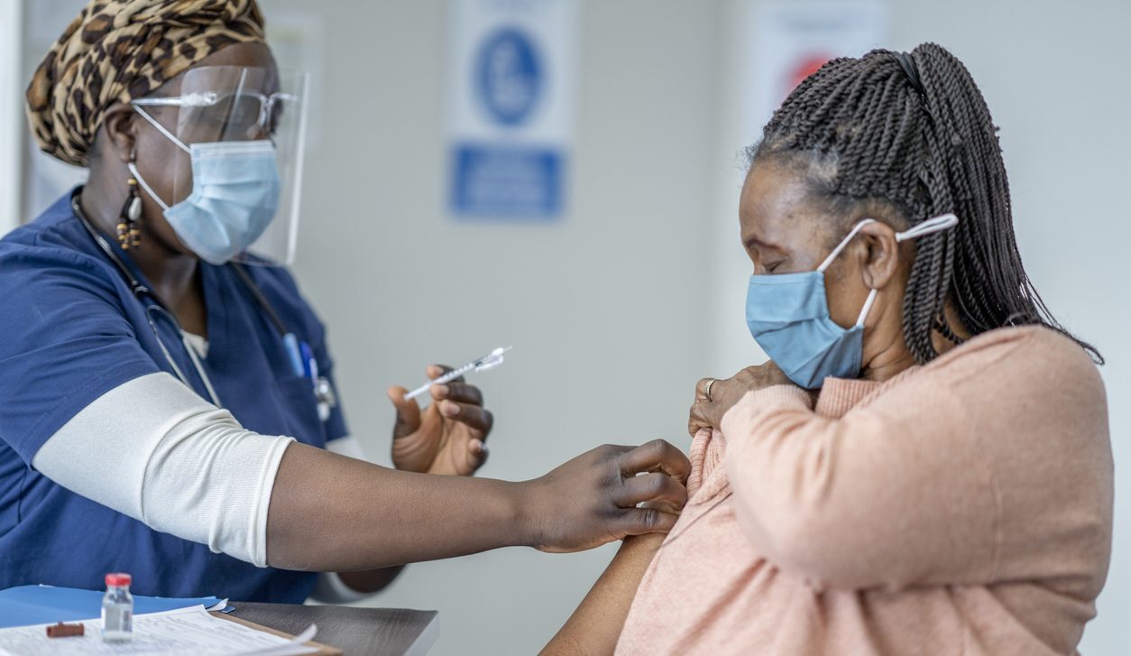 A middle-aged woman receiving a COVID-19 vaccine from a healthcare worker