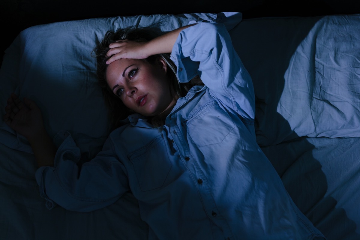 Sleep disorder, insomnia. Young blonde woman lying on the bed awake