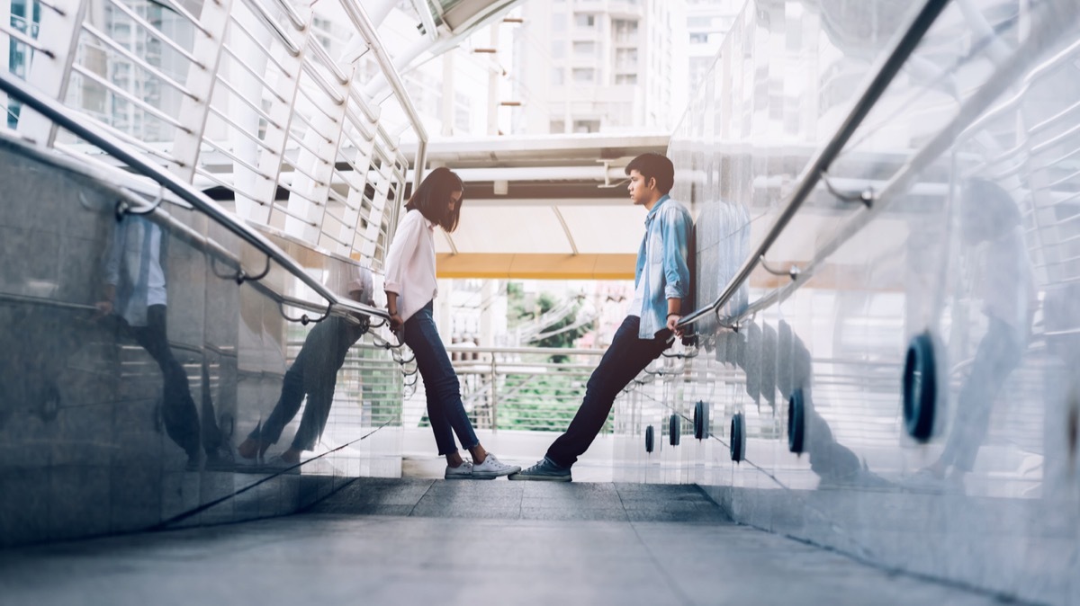 Young couple having a quarrel during a trip together, standing on opposite sides of a ramp