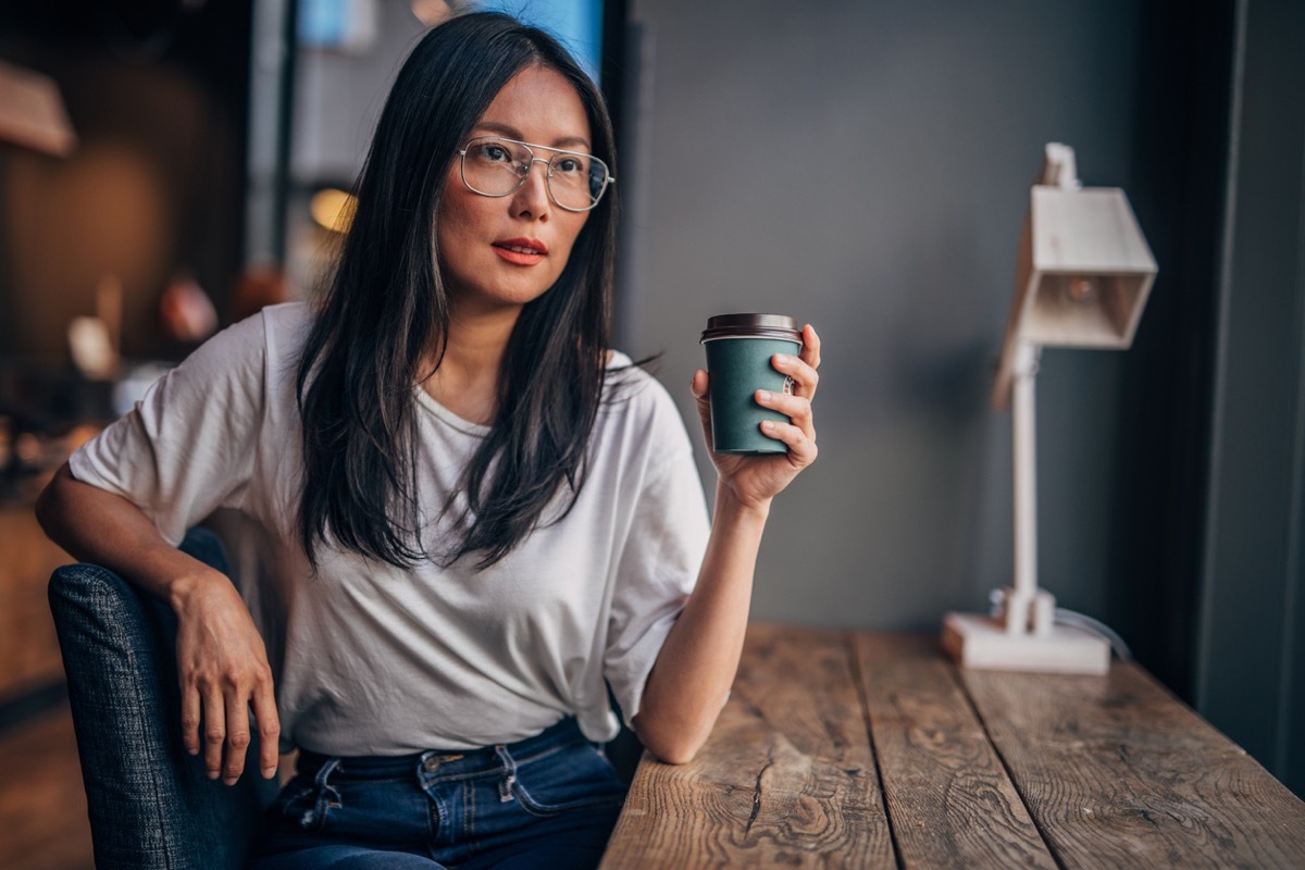 woman with eyeglasses drinking take out coffee.