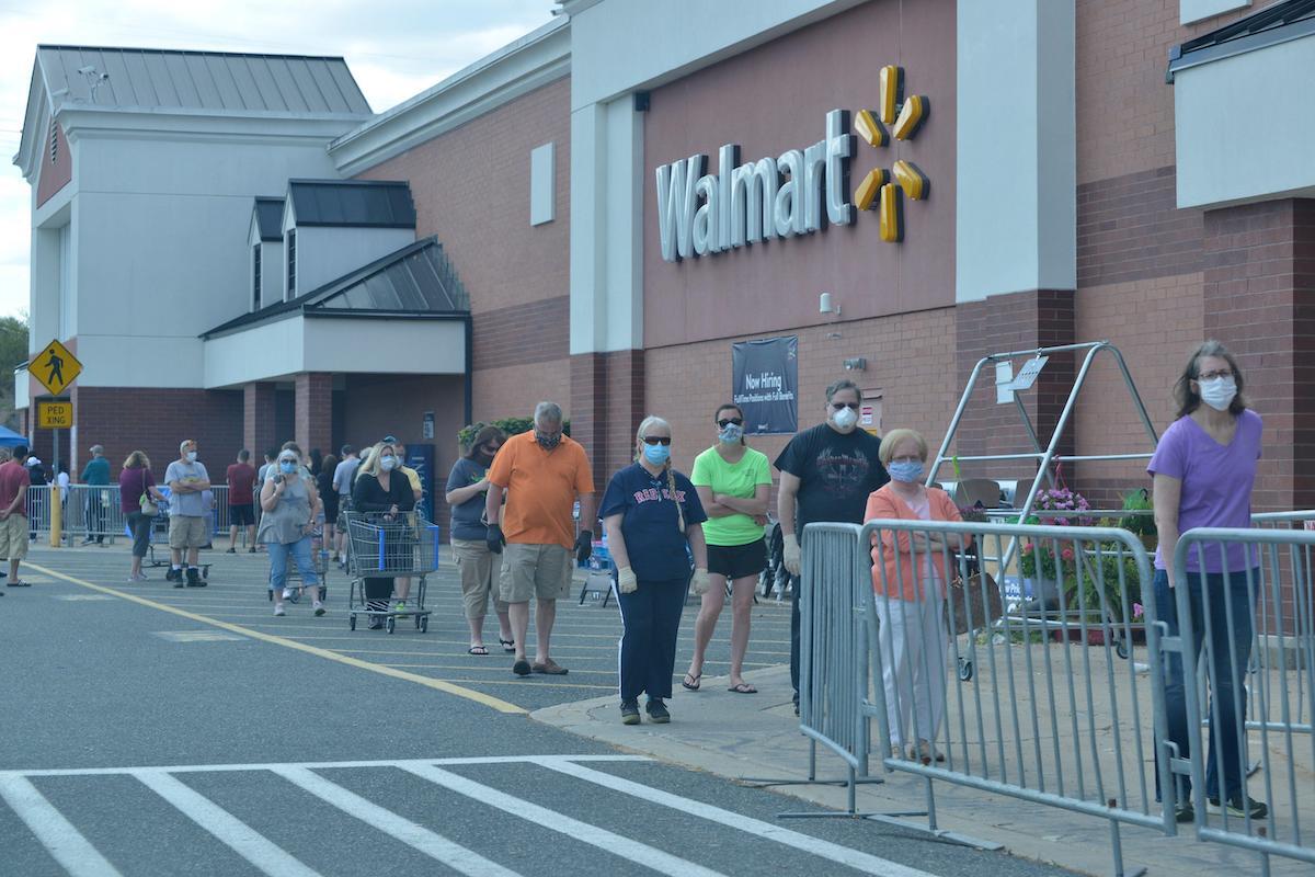 people stand in line outside of a walmart in Massachusetts wearing masks