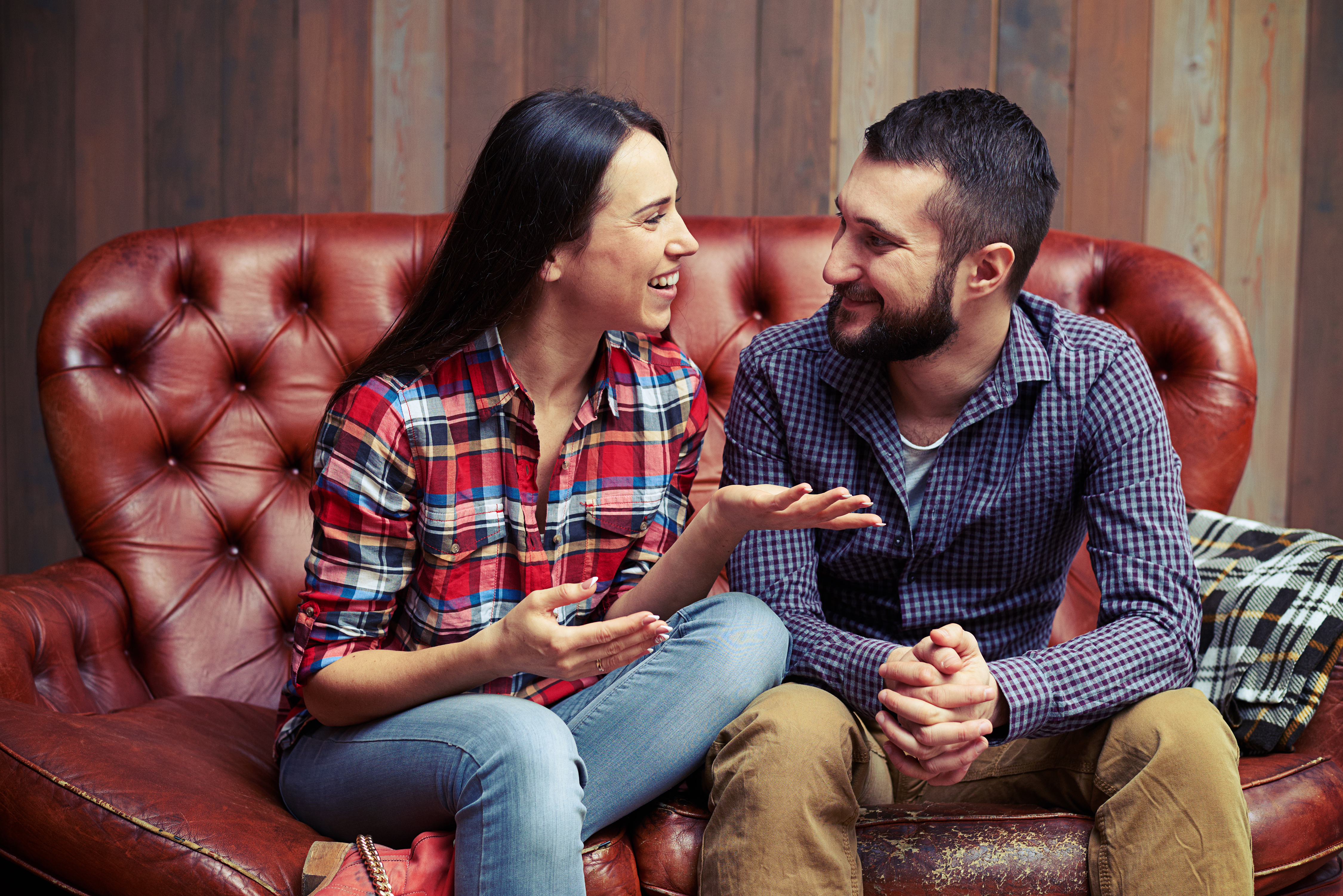 couple smiling and talking on a couch