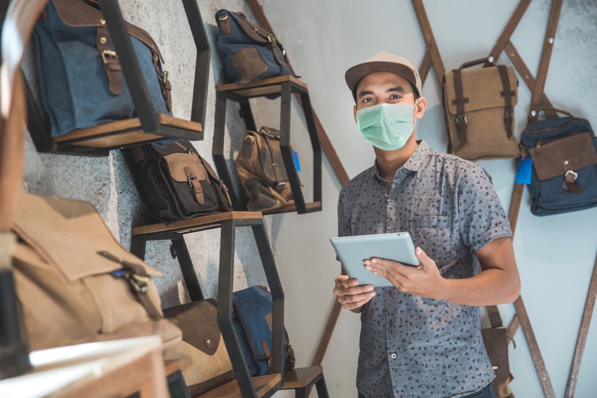 young asian man wearing face mask in backpack store